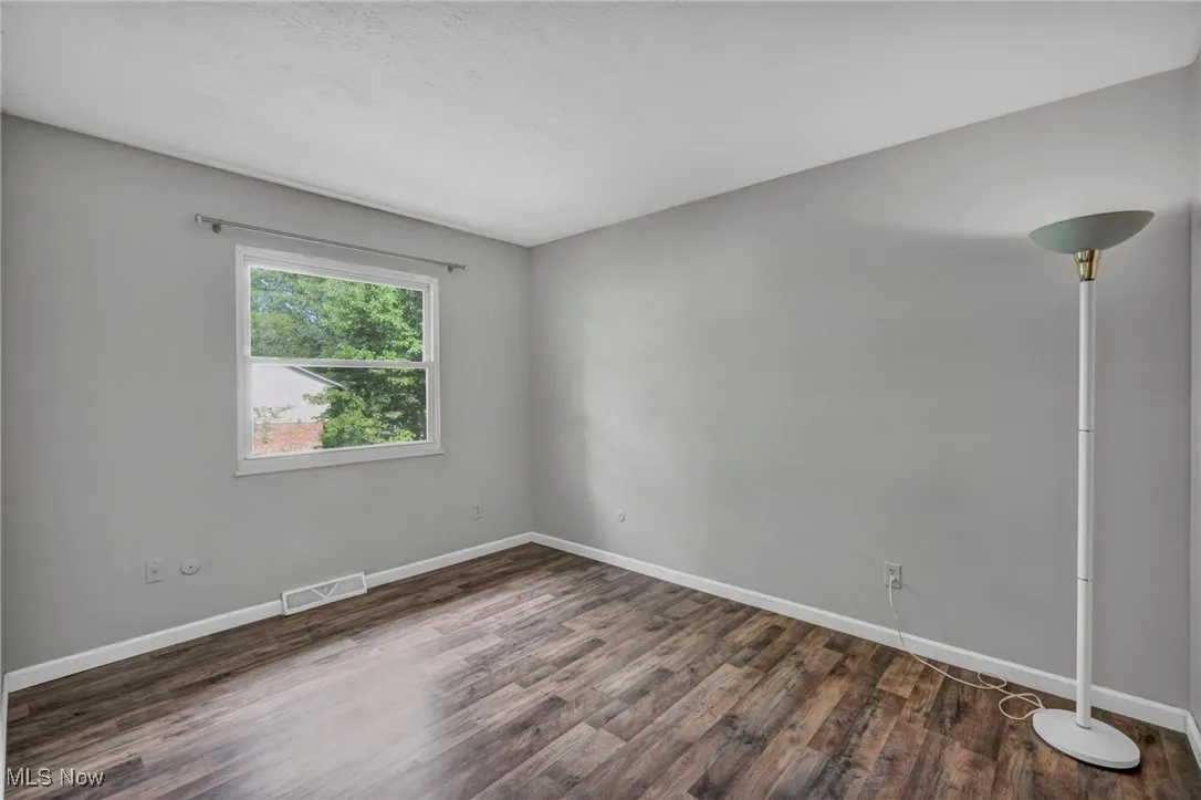 Bedroom with dark wood-type flooring and baseboards