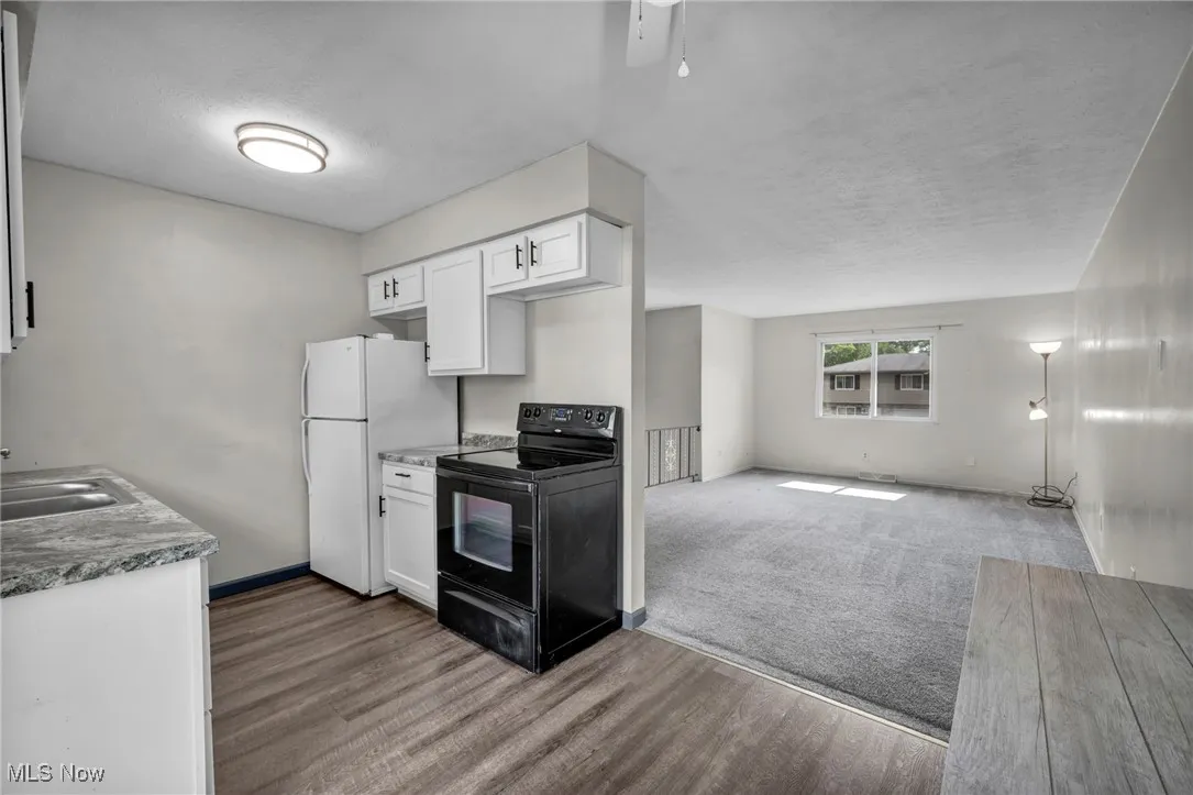 Eat-in Kitchen with sliding doors to deck; electric stove, light lvp flooring, white Shaker cabinets, and ceiling fan