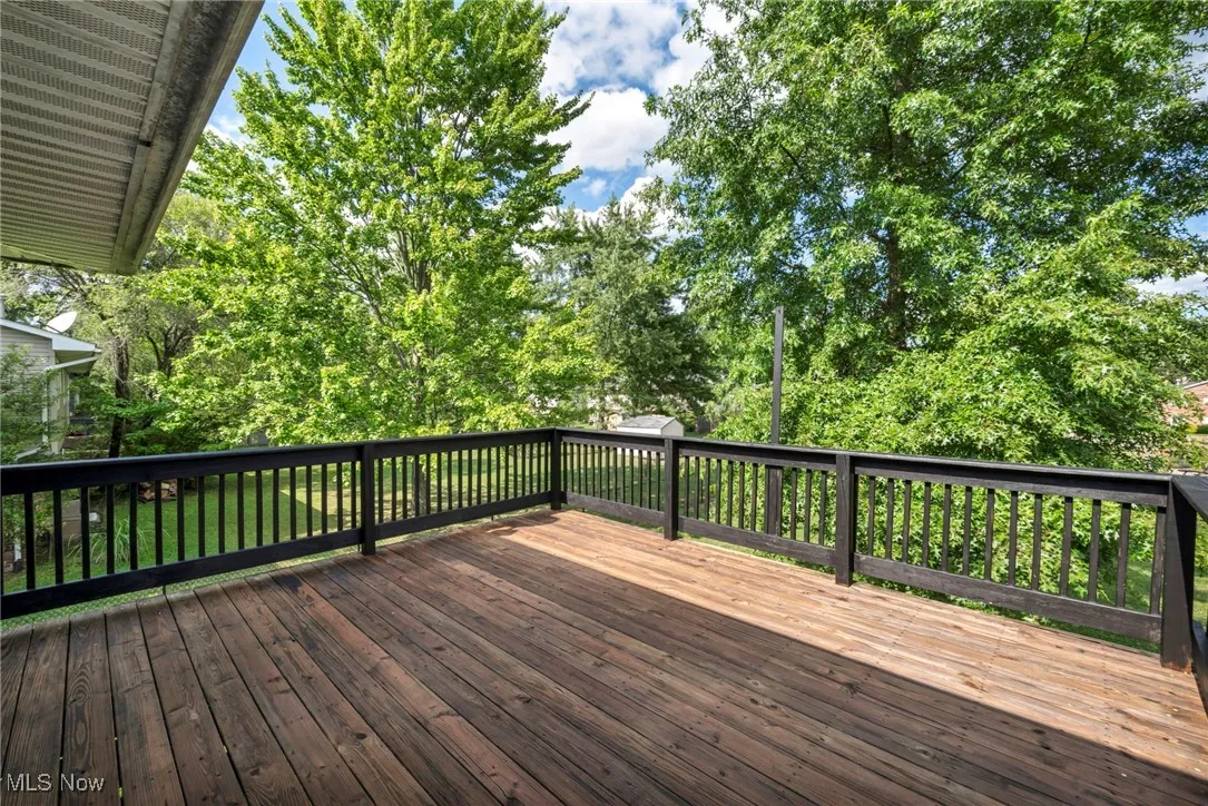 Freshly stained and painted wooden terrace overlooking view of fenced-in backyard and trees