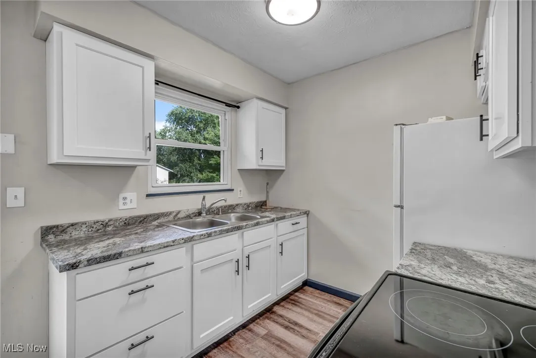 Eat-in Kitchen with sliding doors to deck; electric stove, light lvp flooring, white Shaker cabinets, and ceiling fan