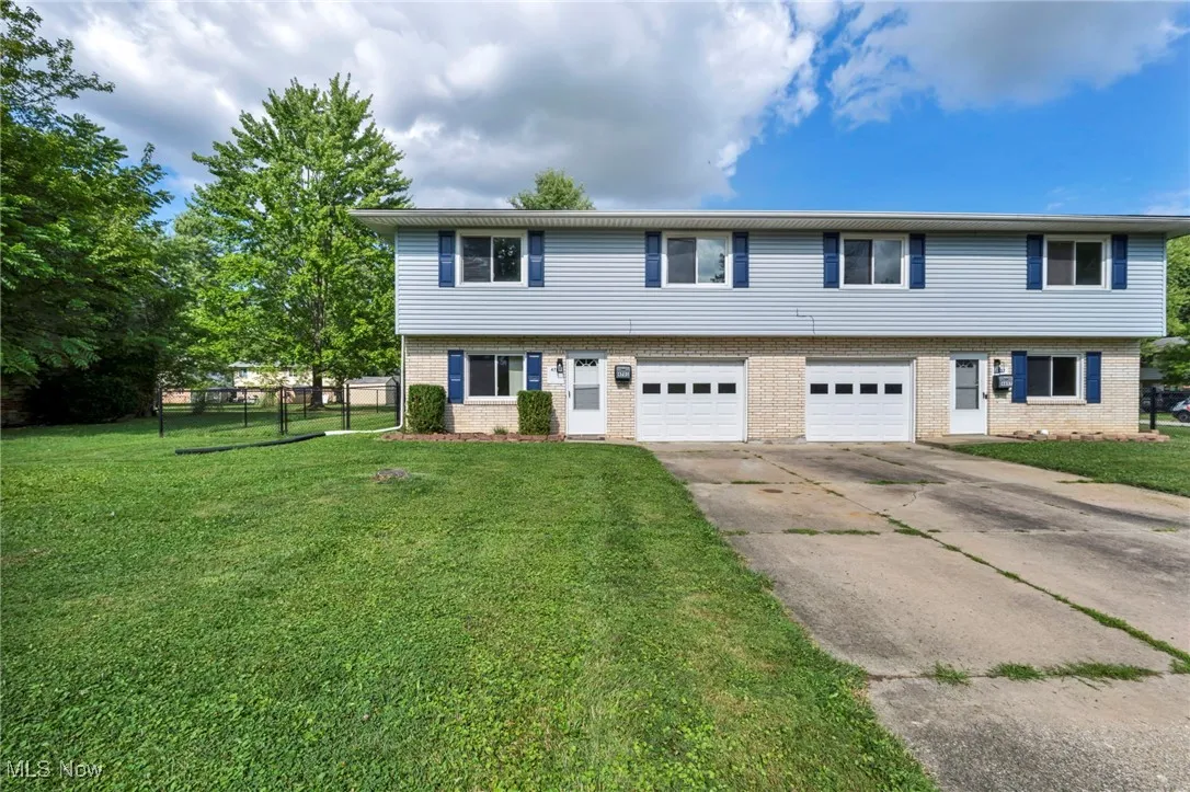 View of 4701 side of Colonial Duplex featuring concrete driveway, an attached garage, and brick siding