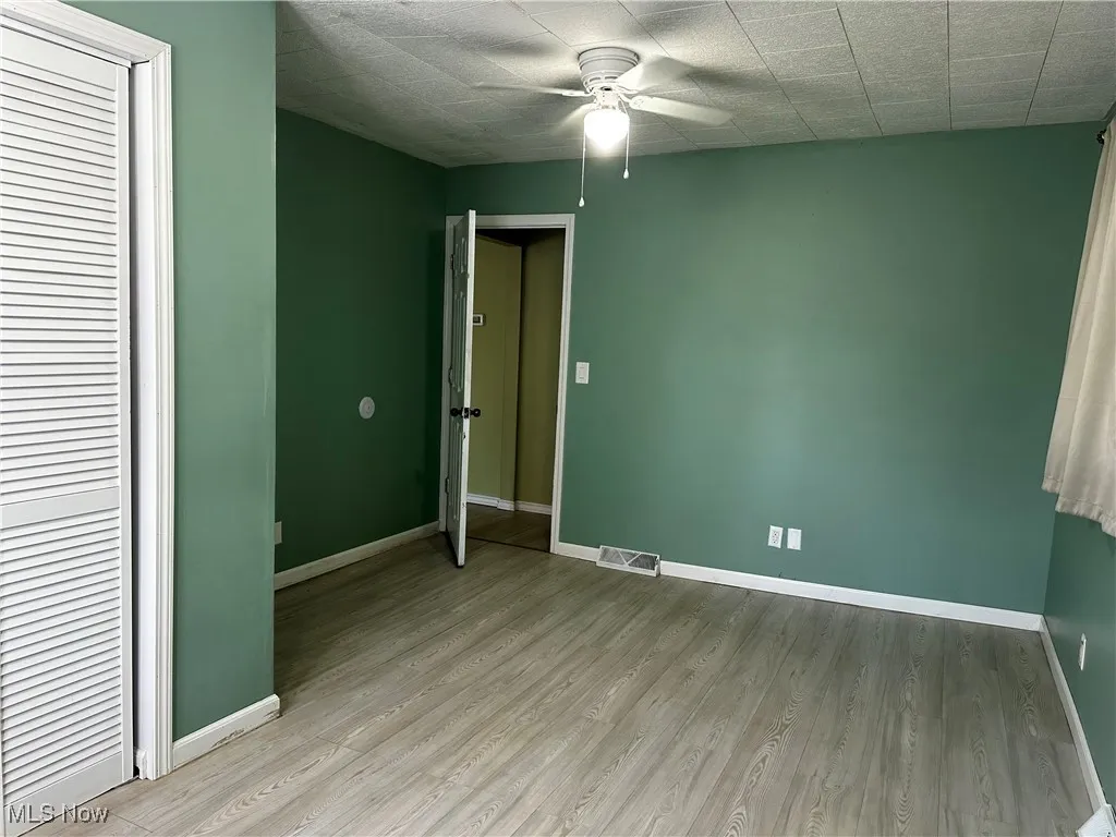 Primary bedroom with ceiling fan and entrance door
