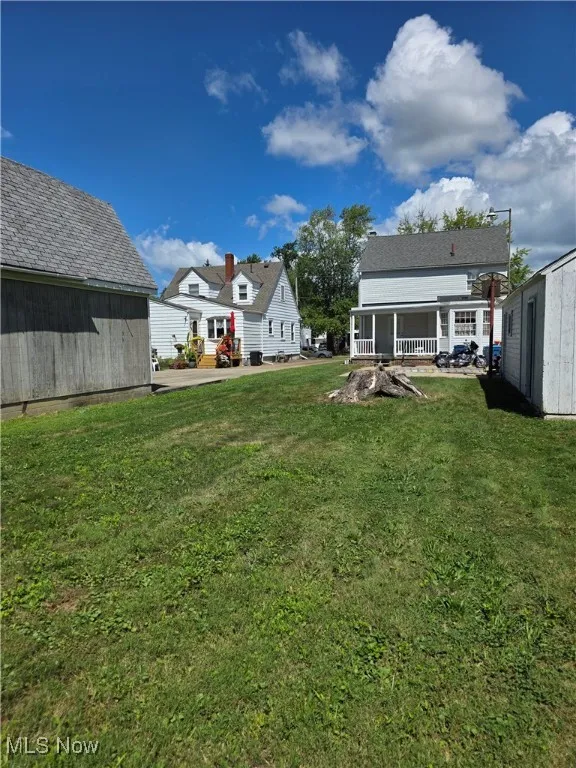 View of green lawn with an outbuilding and a patio