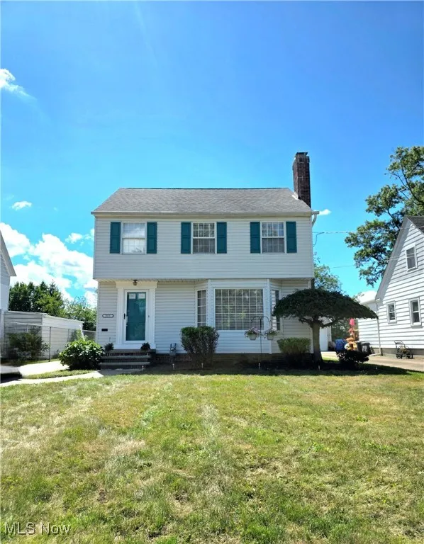 Colonial-style house featuring a chimney and a front yard