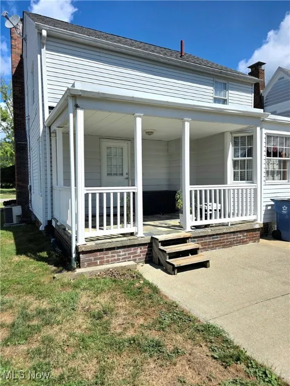 View of front of house featuring covered porch, a chimney, and a front lawn