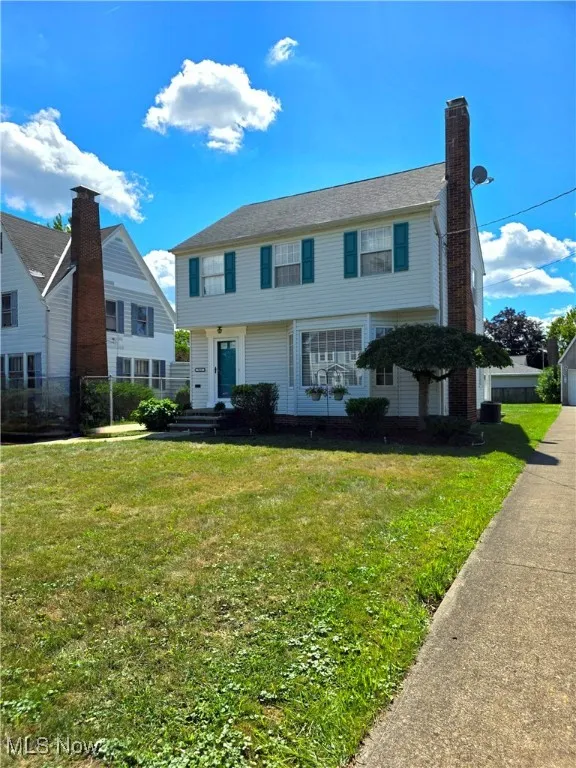 Colonial house featuring a chimney and a front yard