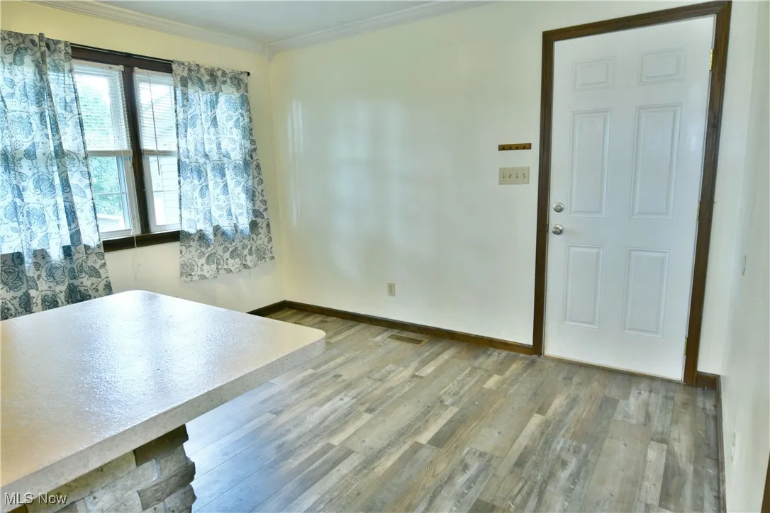 Unfurnished dining area with light wood-style flooring and ornamental molding