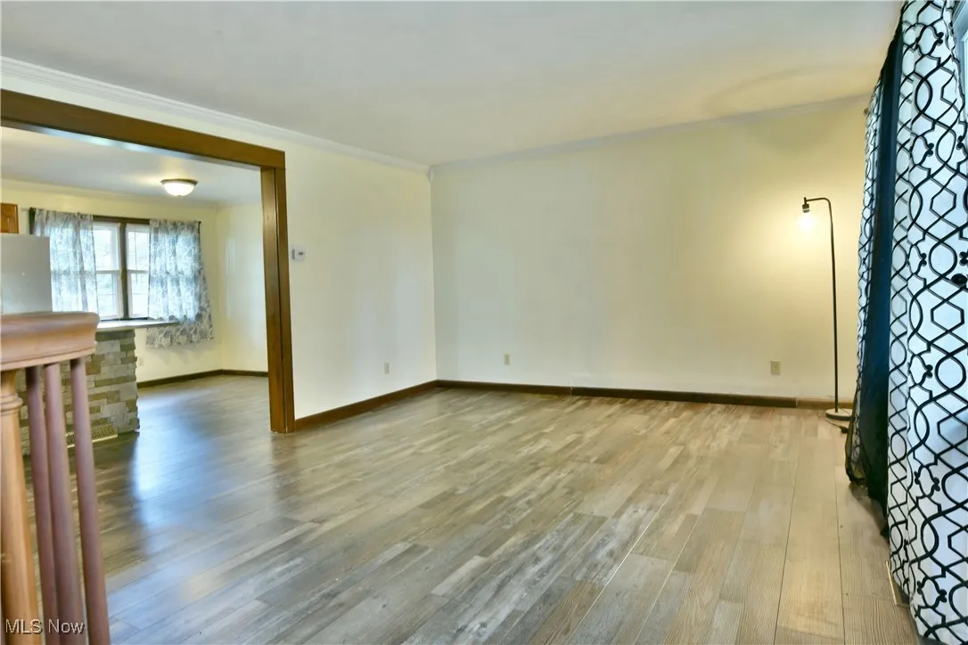Unfurnished living room with light wood-style flooring and ornamental molding