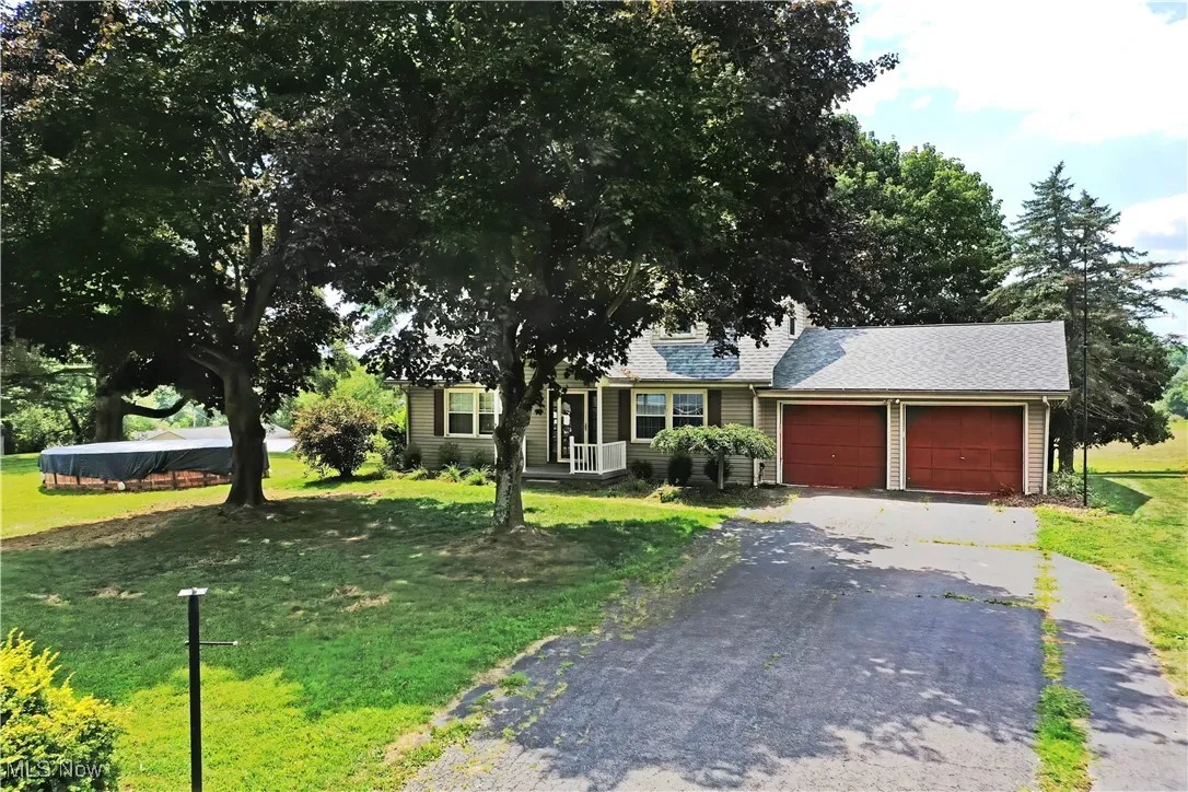 View of front of house with a front yard, asphalt driveway, a garage, and a shingled roof