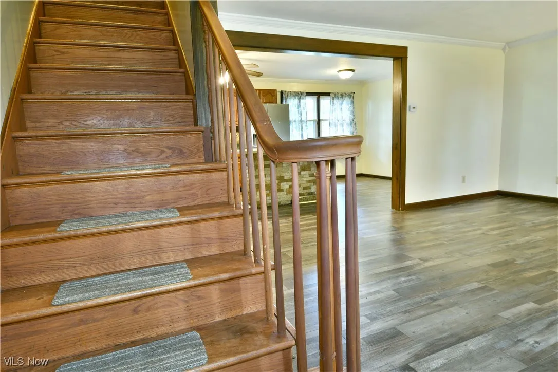 Stairway with wood finished floors and ornamental molding