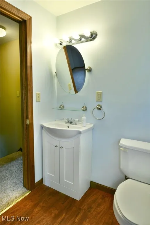 Half bathroom featuring vanity and dark wood-style flooring
