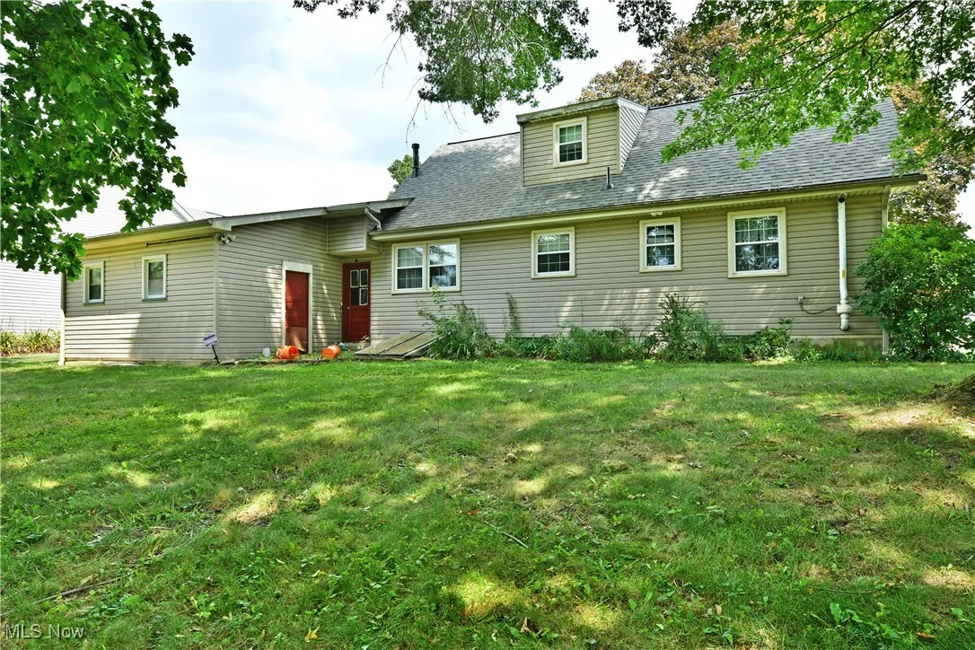 Rear view of house with a yard and roof with shingles