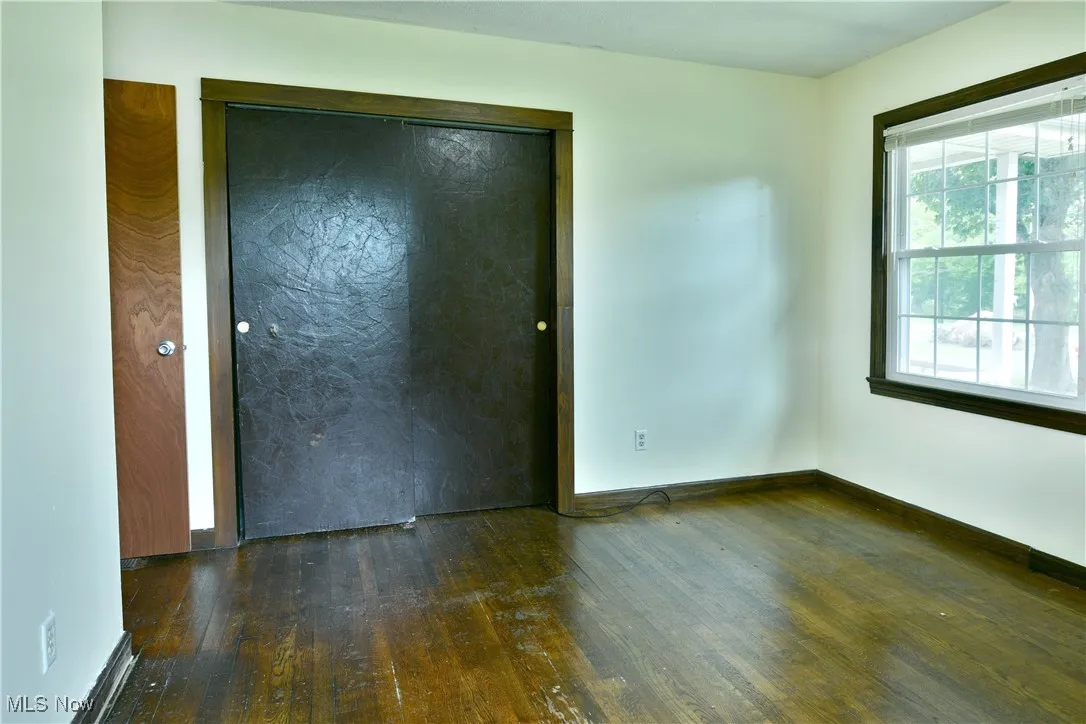 Unfurnished bedroom featuring dark wood-type flooring and a closet