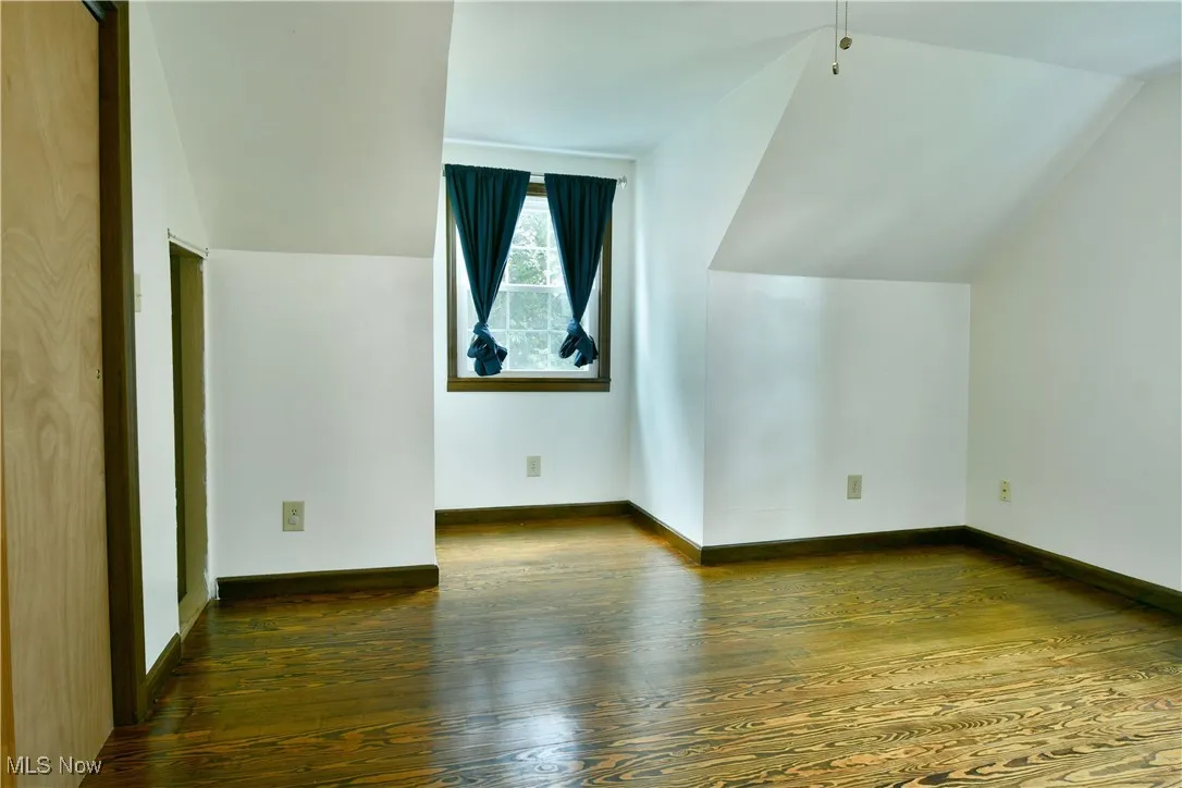 Bonus room with vaulted ceiling and dark wood-style floors