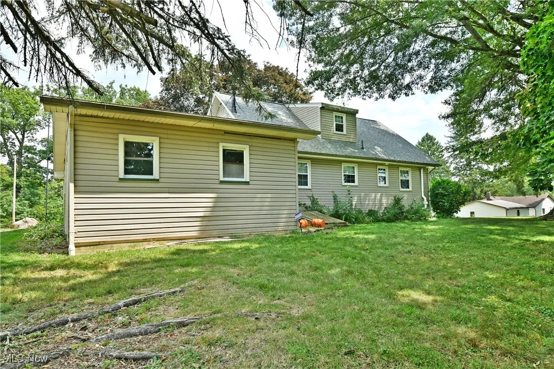 Back of house featuring a lawn and a shingled roof