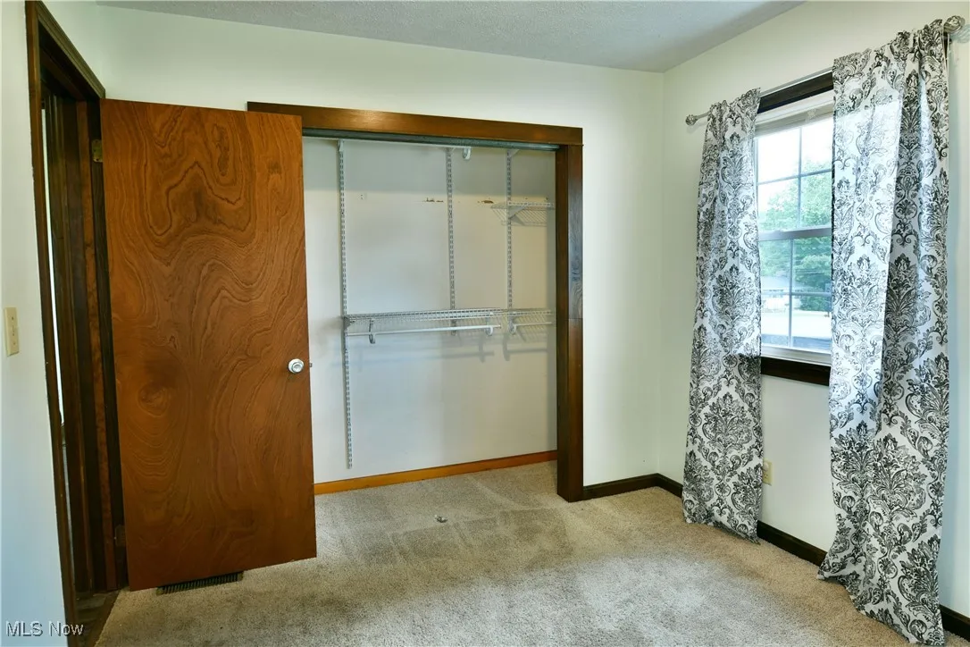 Unfurnished bedroom with light colored carpet and a closet