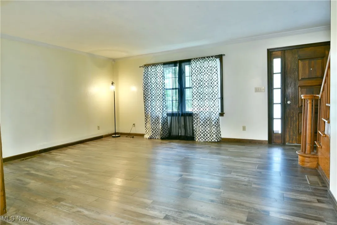 Unfurnished room featuring ornamental molding, hardwood / wood-style floors, and stairway