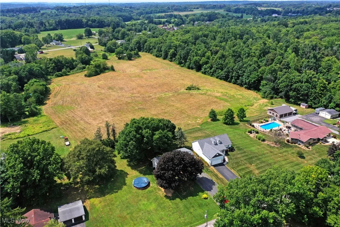 Aerial view of property and surrounding area featuring a pool area and rural landscape