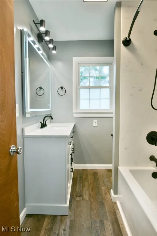 Bathroom with dark wood finished floors, vanity, and shower / bath combination