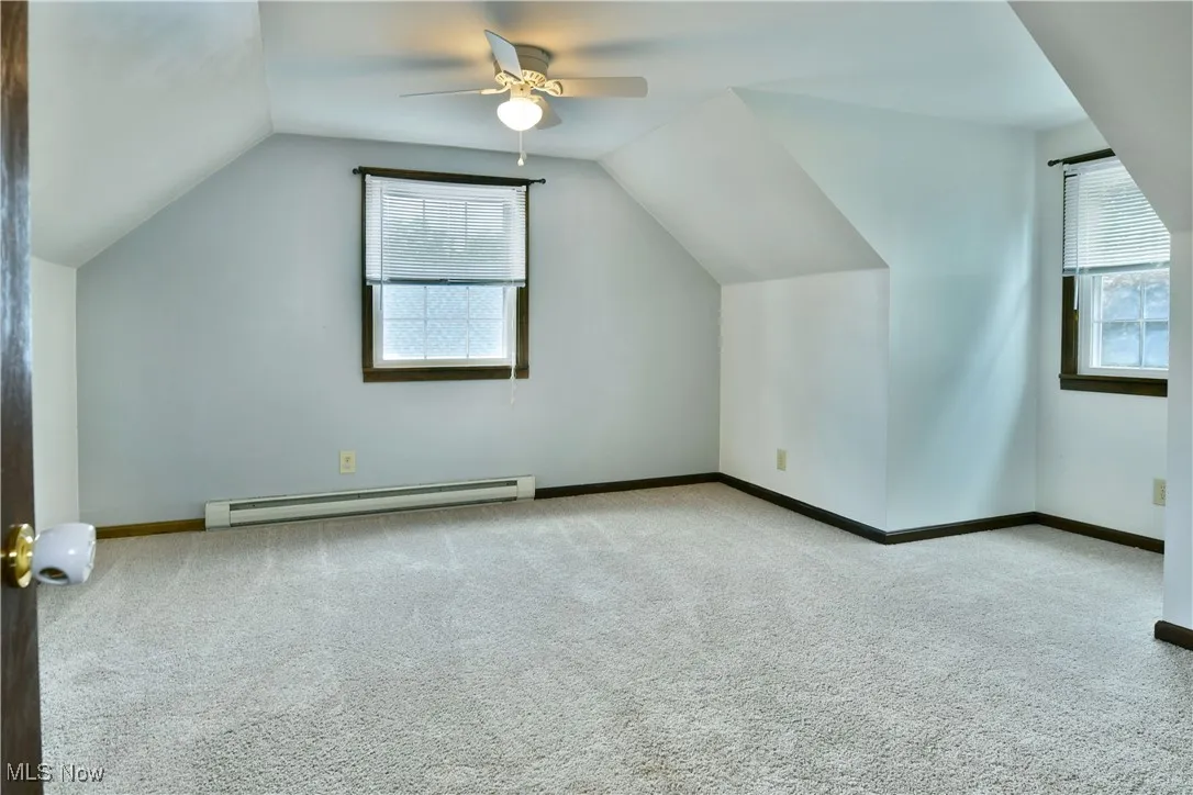 Additional living space with light colored carpet, vaulted ceiling, and a baseboard heating unit