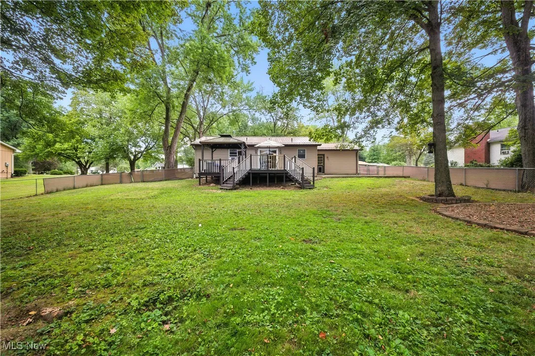 Back of house with stairway, a fenced backyard, and a wooden deck
