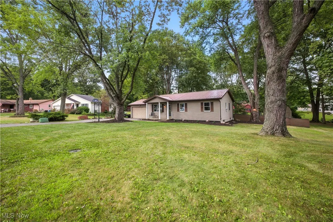 Ranch-style house featuring a metal roof, view of wooded area, and a front yard