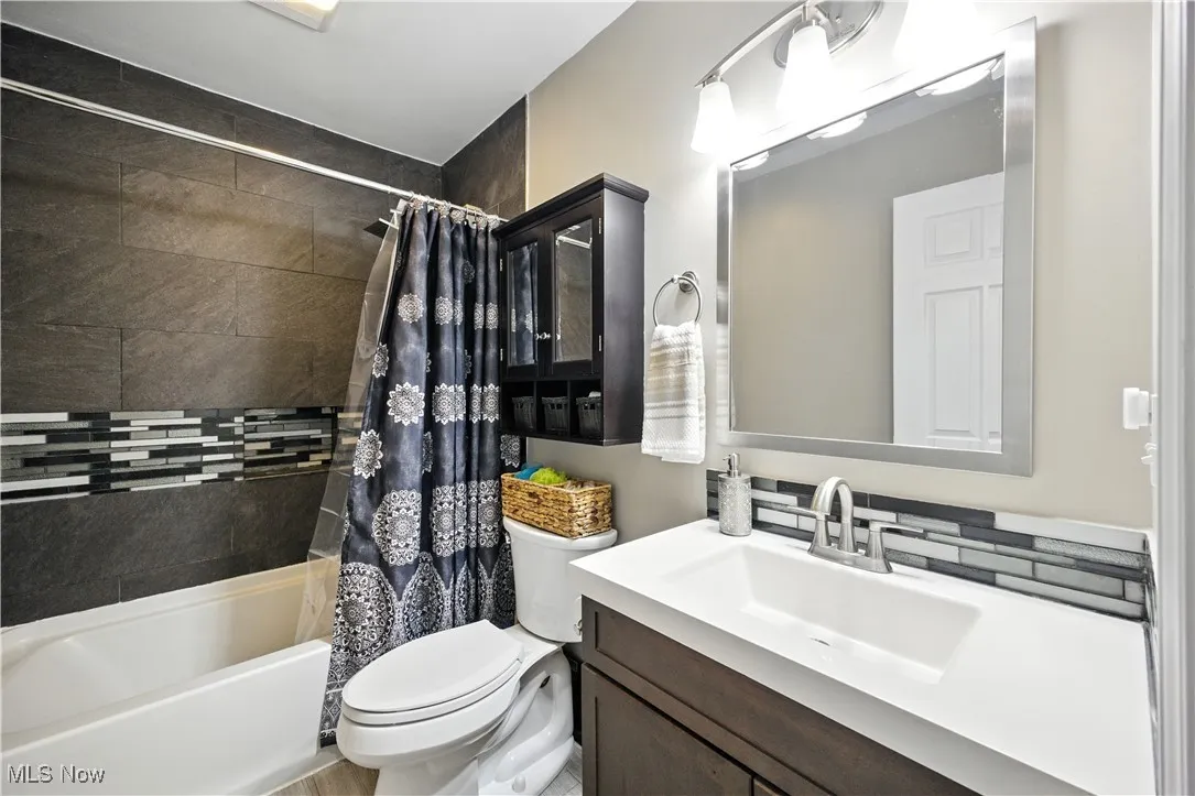 Bathroom featuring shower / bath combination with curtain and vanity