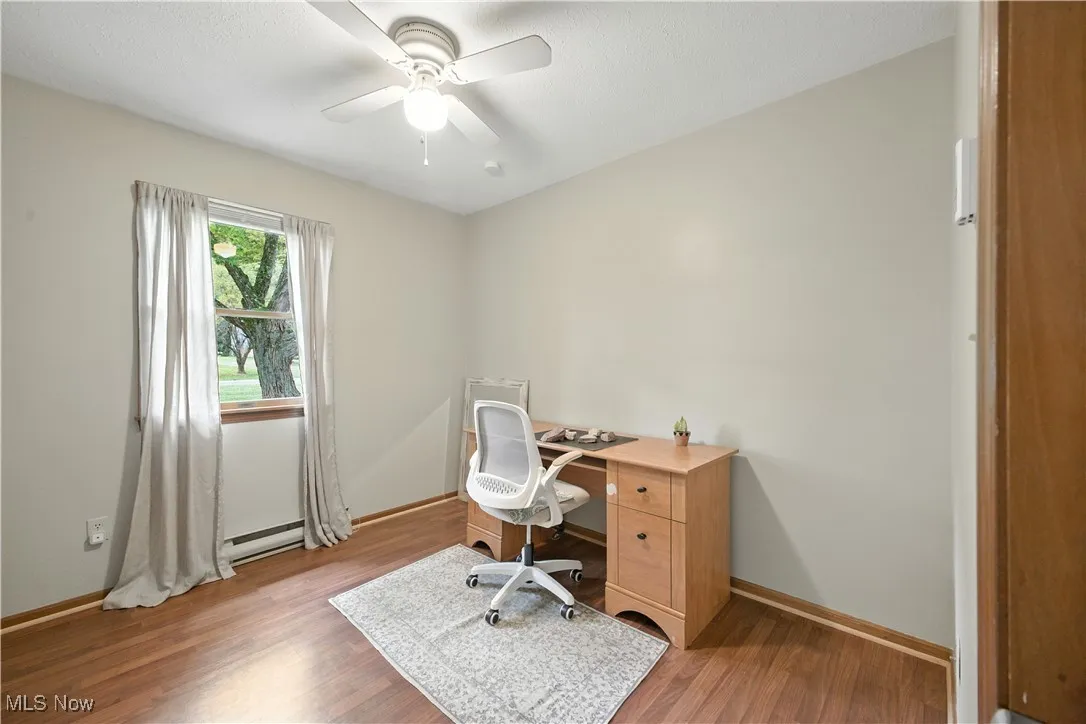 Office space with light wood-style flooring, a ceiling fan, and a baseboard radiator