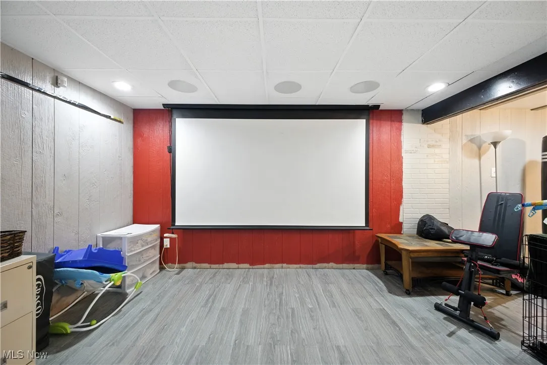 Home theater featuring a paneled ceiling, wood finished floors, and wooden walls