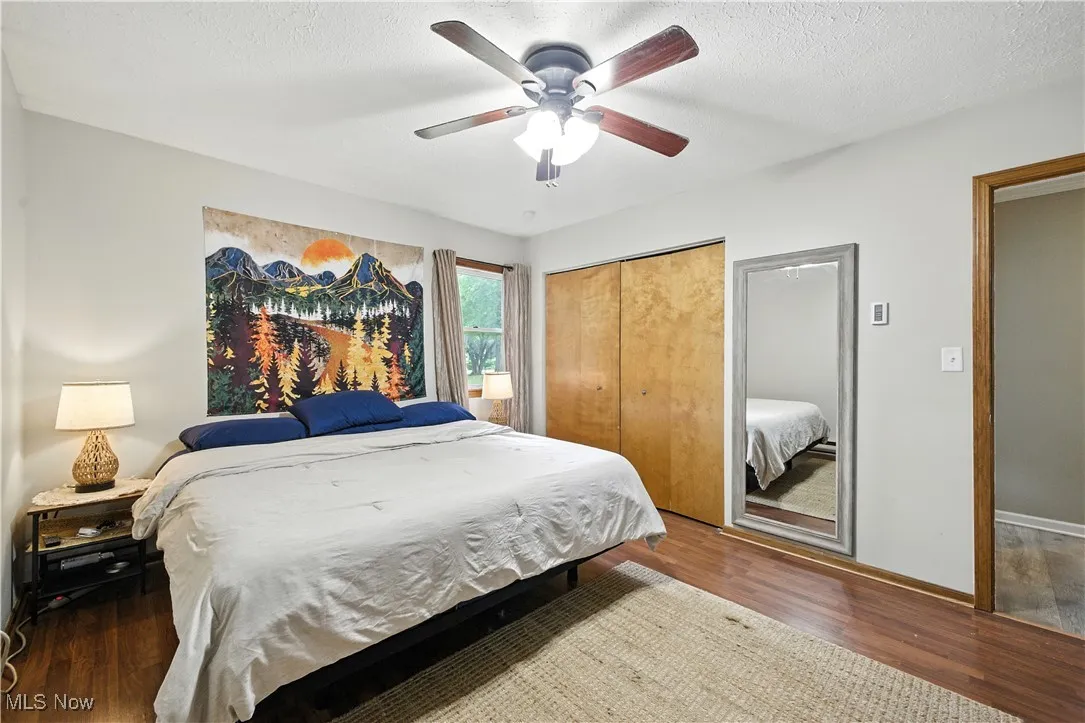 Bedroom with wood finished floors, a closet, ceiling fan, and a textured ceiling