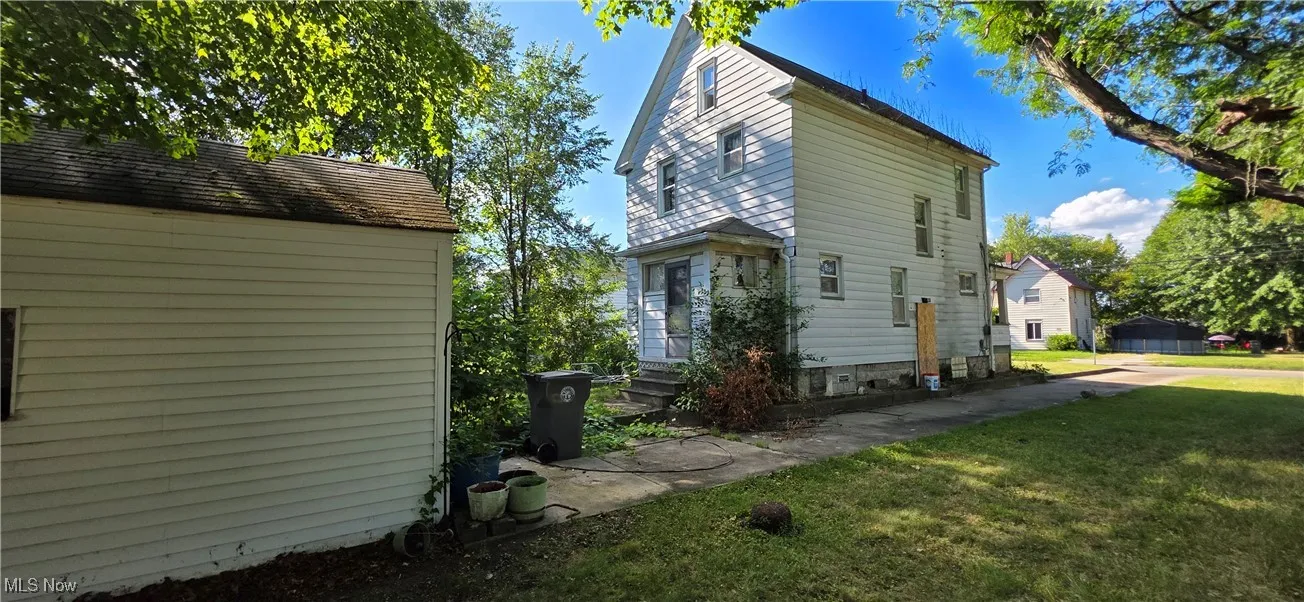 View of home's exterior with a lawn and an outbuilding