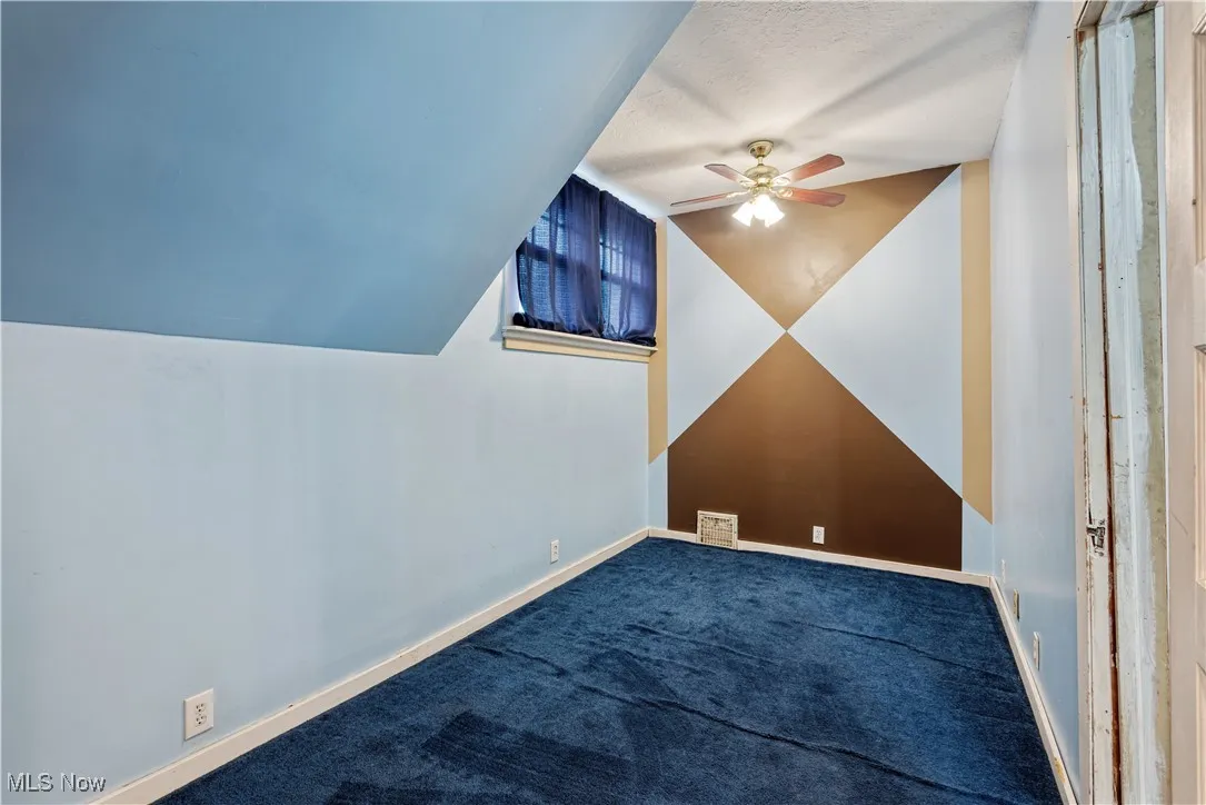 Additional living space featuring lofted ceiling, carpet floors, a ceiling fan, and a textured ceiling