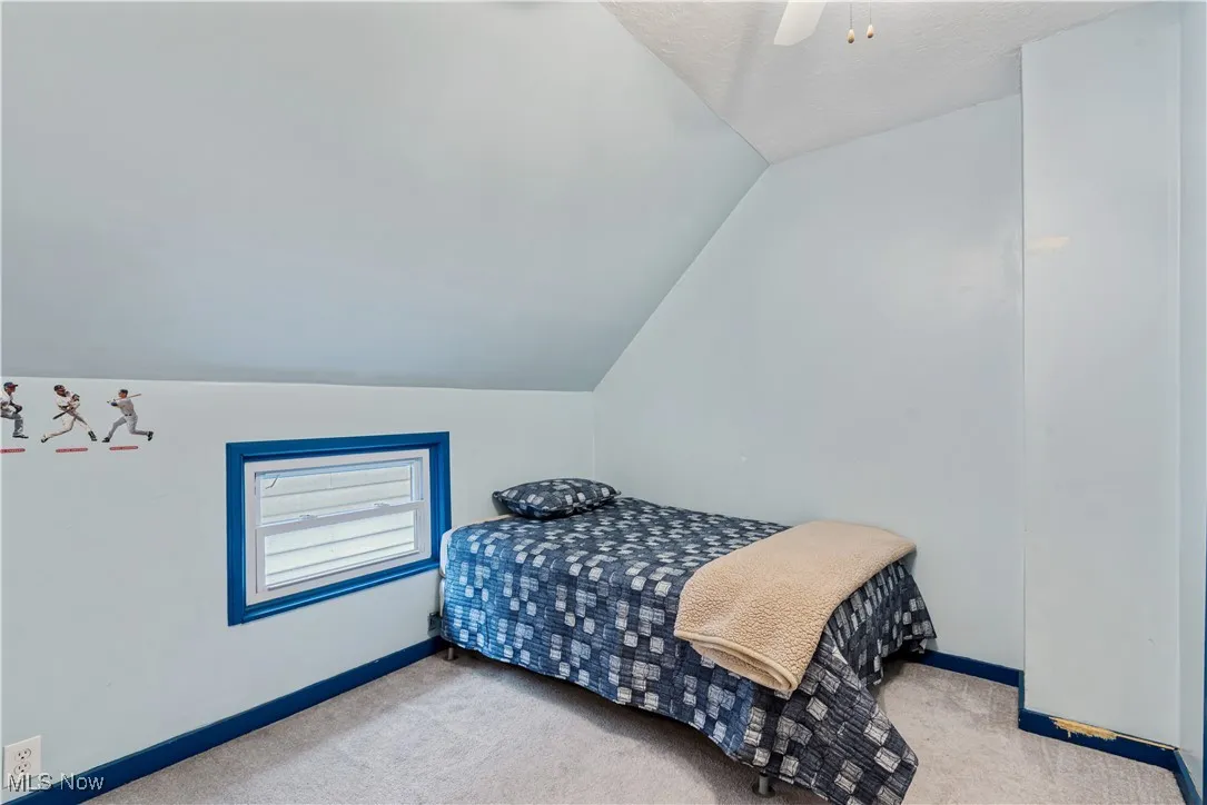 Bedroom with vaulted ceiling, carpet floors, and ceiling fan