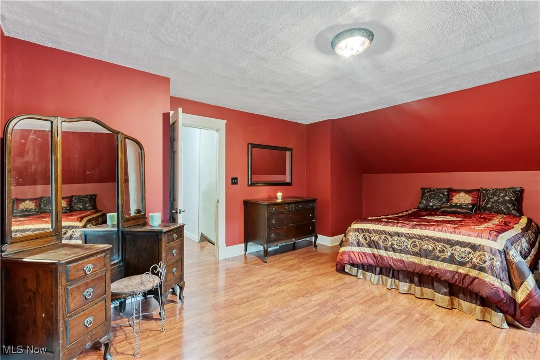 Bedroom featuring a textured ceiling, wood finished floors, and vaulted ceiling