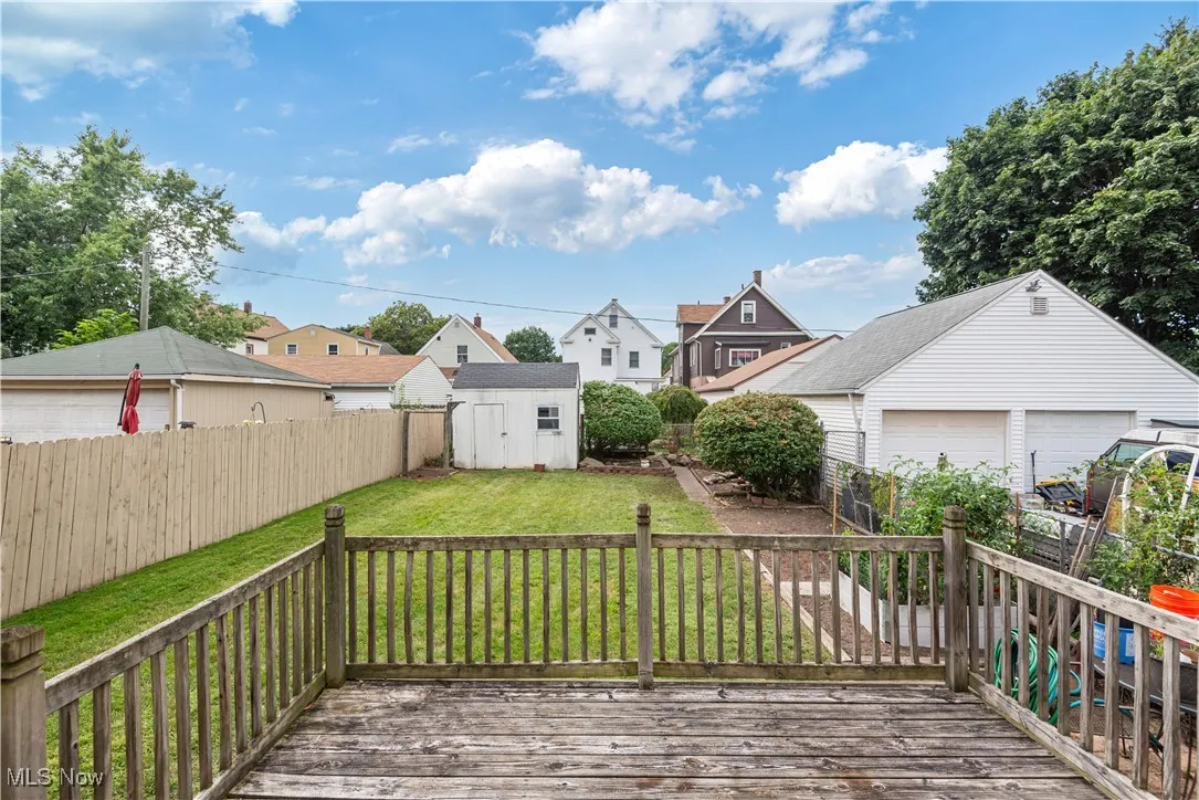 Wooden deck featuring a residential view, a fenced backyard, a storage shed, and a garage