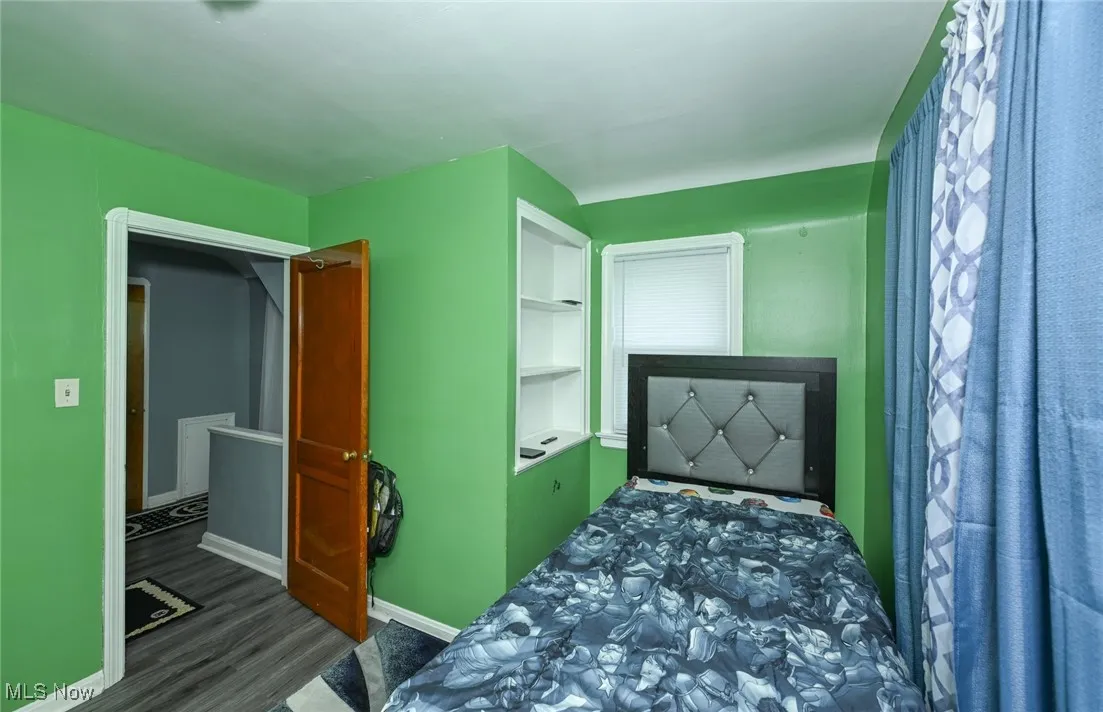 Bedroom with baseboards and dark wood-type flooring