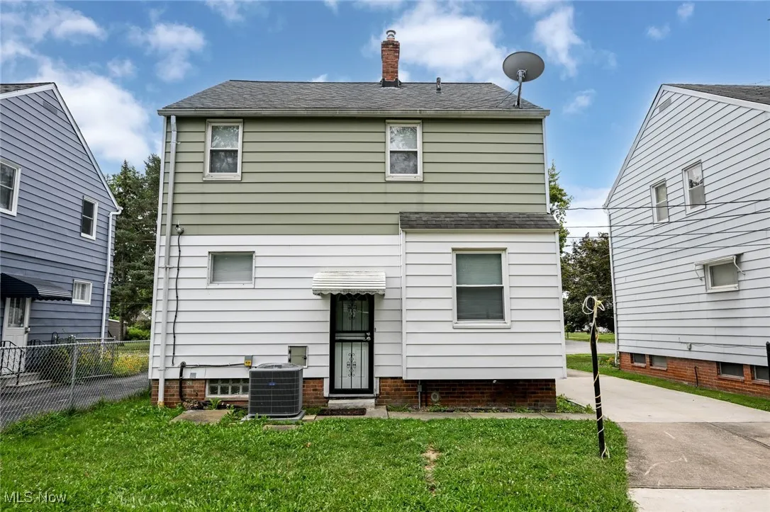 Back of house featuring a shingled roof, a chimney, and driveway