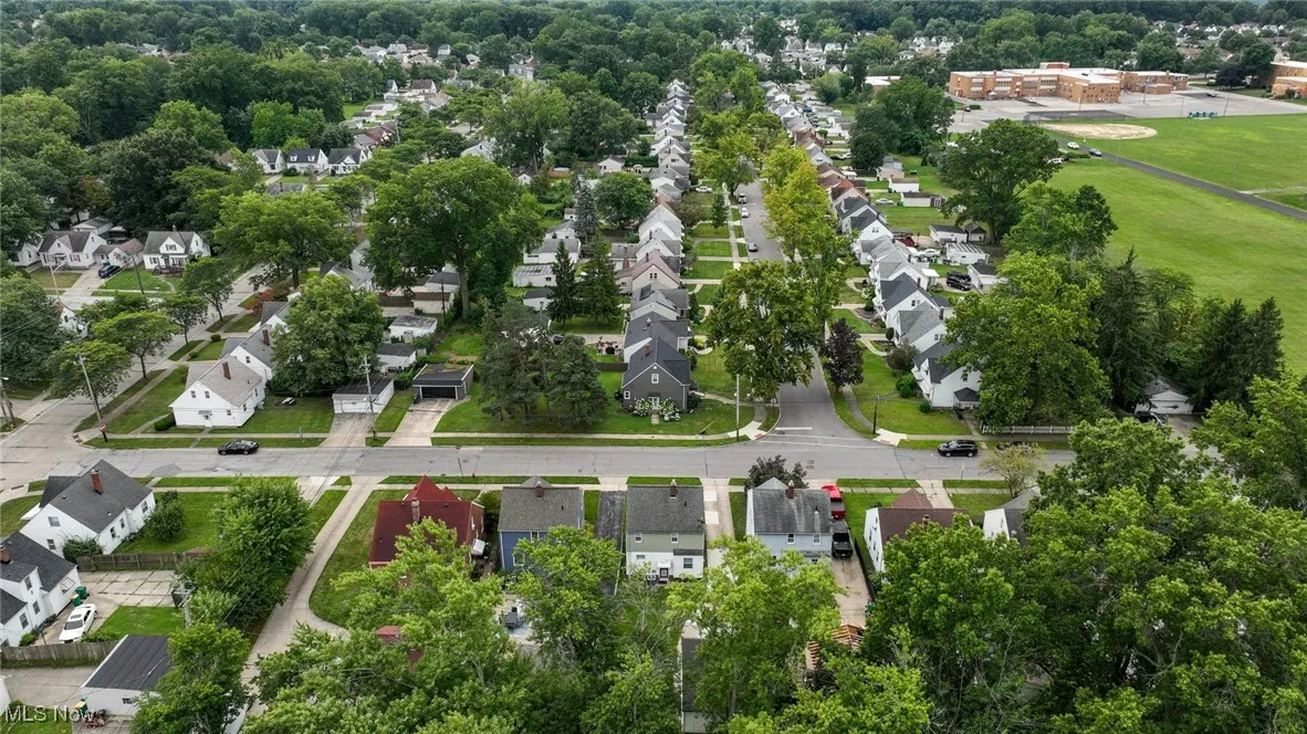 Aerial view of property and surrounding area featuring nearby suburban area and a tree filled landscape