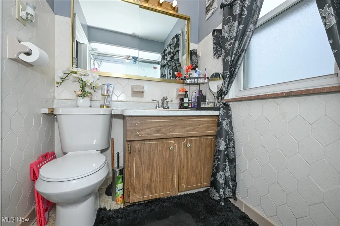 Bathroom featuring vanity, backsplash, and tile walls