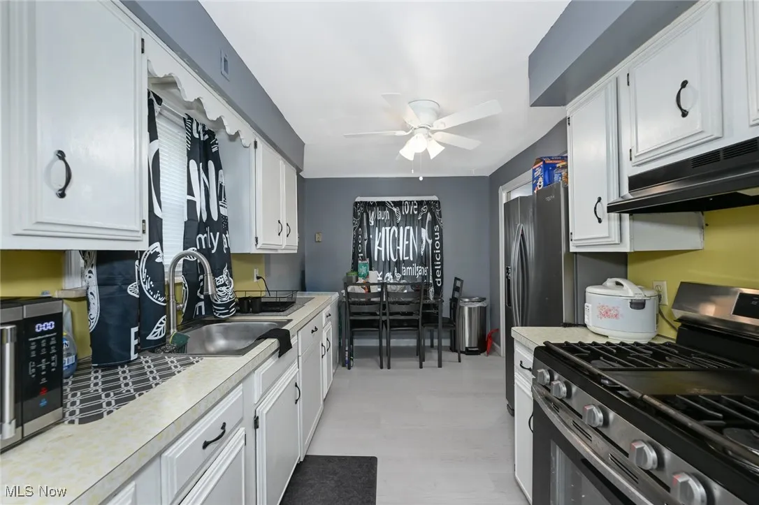 Kitchen featuring appliances with stainless steel finishes, white cabinetry, light countertops, and under cabinet range hood