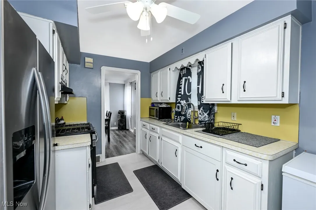 Kitchen featuring appliances with stainless steel finishes, white cabinetry, light countertops, and a ceiling fan