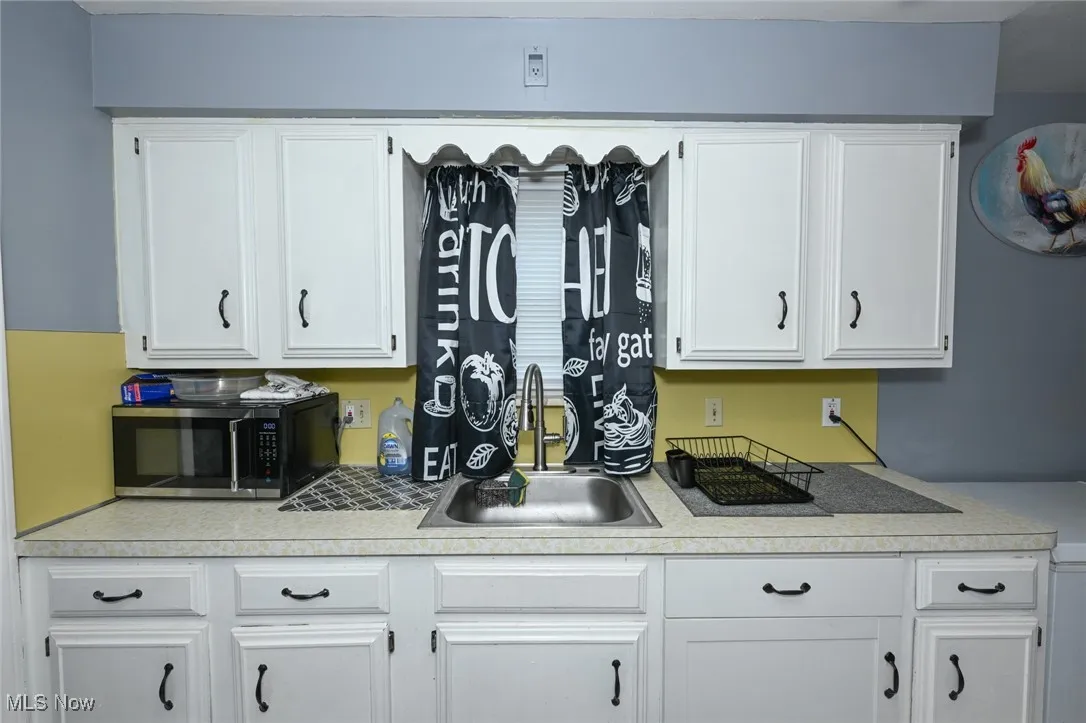 Kitchen view of light countertops, white cabinets, and stainless steel microwave