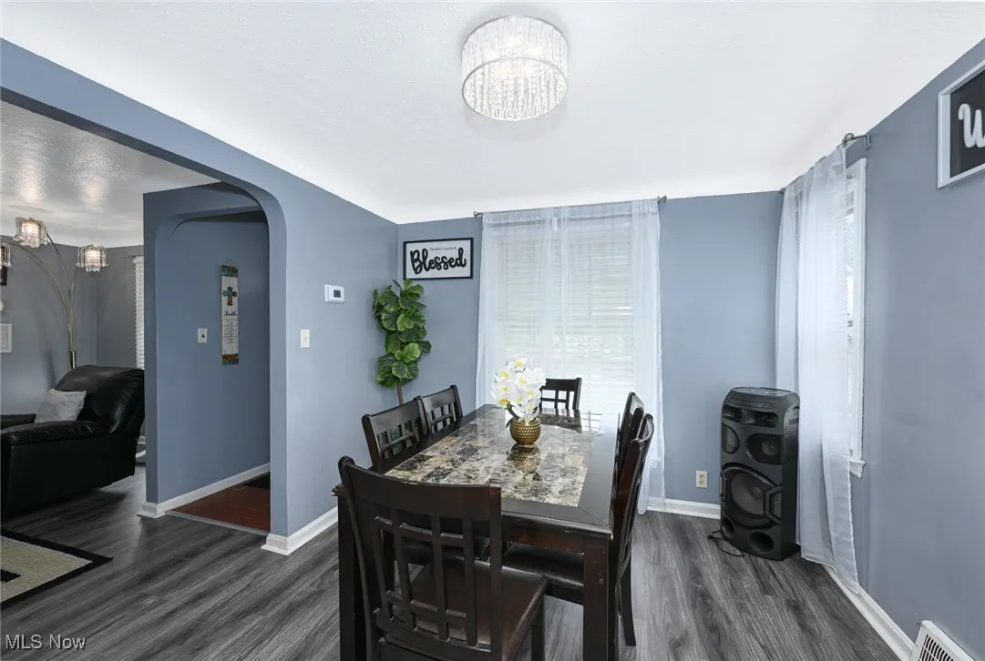 Dining room featuring arched walkways, dark wood-style floors, and a chandelier