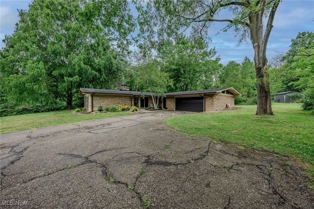 Mid-century home featuring a garage, a front lawn, driveway, and a chimney