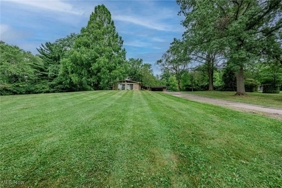 View of green lawn featuring a carport and driveway