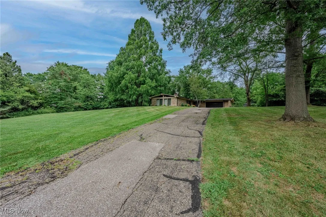 View of front of property featuring a front yard, driveway, a chimney, and a carport