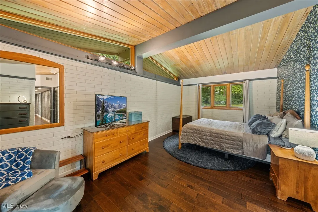 Bedroom with brick wall, wood-type flooring, and wooden ceiling