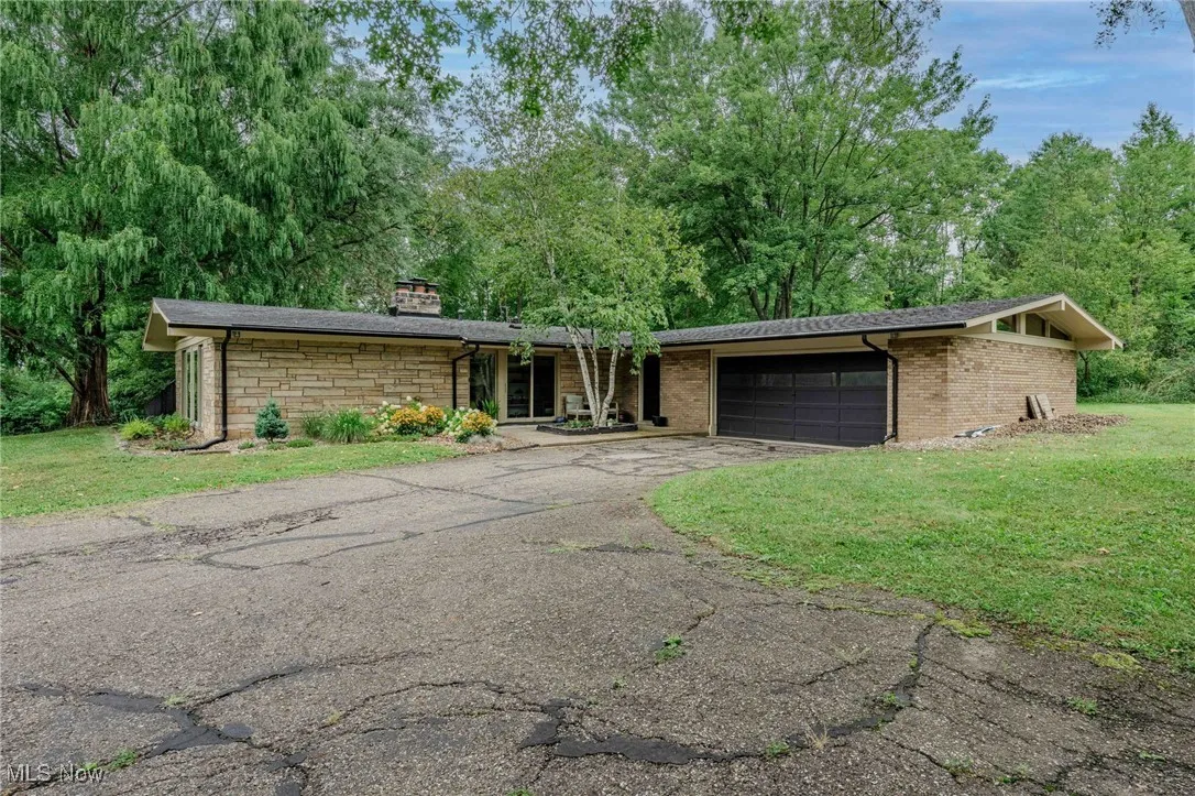 Mid-century home with driveway, a front yard, a garage, and a chimney