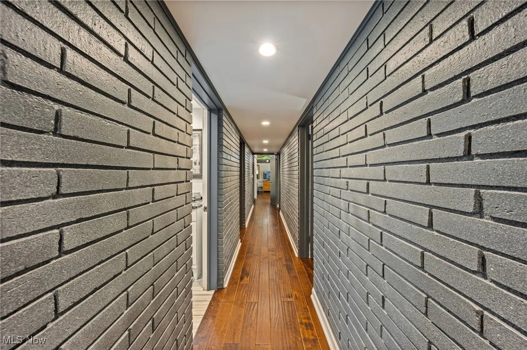 Corridor with recessed lighting, dark wood-style flooring, and brick wall