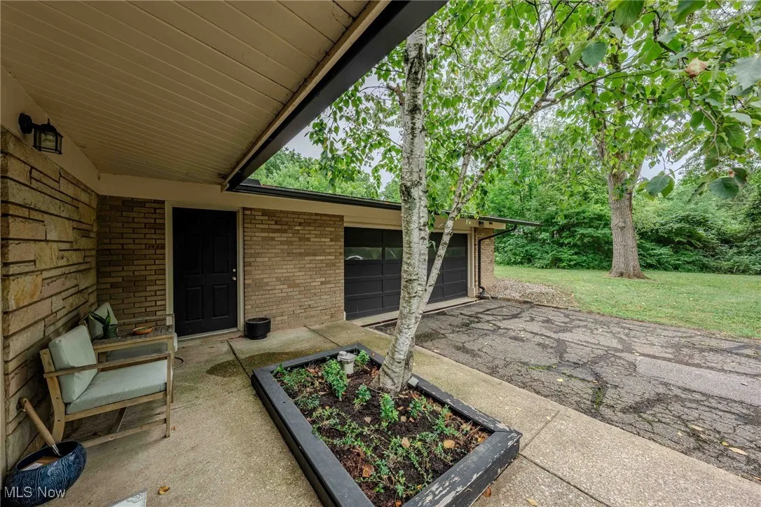 View of patio / terrace featuring asphalt driveway, an attached garage, and a vegetable garden